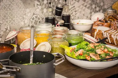 a table with a bowl of salad and a pot of food at Hotel Lavender in Kraków