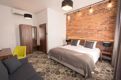 a bedroom with a bed and a brick wall at Hotel Lavender in Kraków