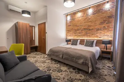 a bedroom with a bed and a brick wall at Hotel Lavender in Kraków