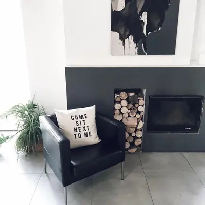 a black chair with a pillow on it next to a fireplace at Pradnik Valley Lodge in Prądnik Korzkiewski