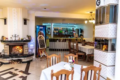 a restaurant with a fireplace and a tables and chairs at Hotel Artur in Oświęcim