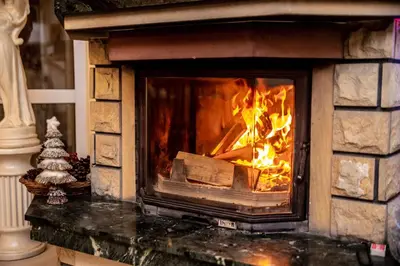 a stone fireplace with a fire in it at Hotel Artur in Oświęcim