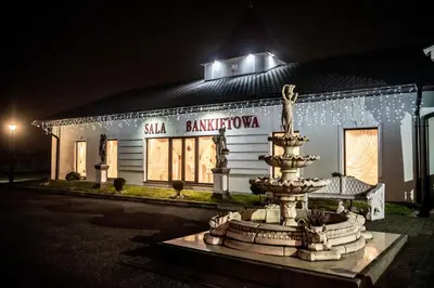 a building with a fountain in front of it at night at Hotel Artur in Oświęcim