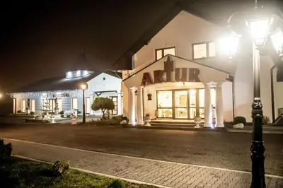 a building with a sign on the front of it at night at Hotel Artur in Oświęcim