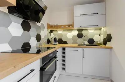 a kitchen with white cabinets and black and white tiles at Old Town Premium Queen`s Apartments in Kraków