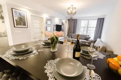 a table with plates and glasses and a bottle of wine at Old Town Premium Queen`s Apartments in Kraków