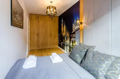 a bedroom with a blue bed and a chandelier at Old Town Premium Queen`s Apartments in Kraków