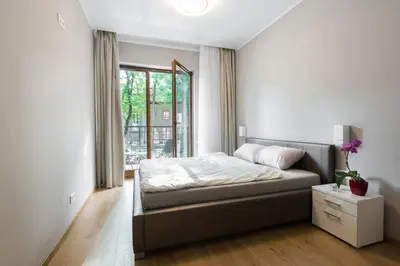 a bedroom with a bed and a large window at Pawia Apartments Modern in Kraków