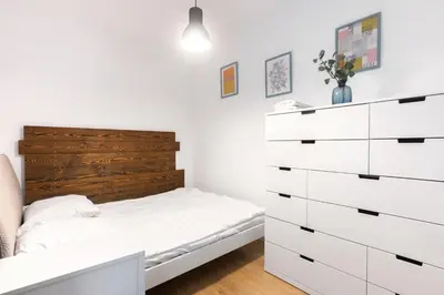 a bedroom with a bed and a chest of drawers at Pawia Apartments Modern in Kraków