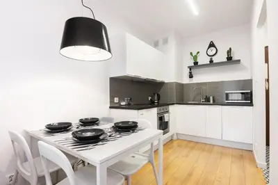 a white kitchen with a white table and chairs at Pawia Apartments Modern in Kraków