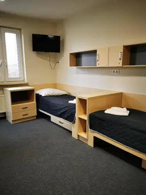 a room with two beds and a flat screen tv at Dom Studencki Zaułek in Kraków