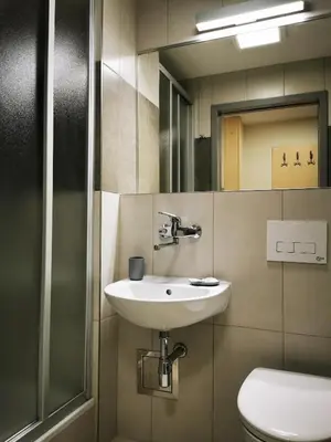 a bathroom with a sink and a toilet and a mirror at Dom Studencki Zaułek in Kraków
