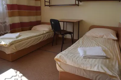 a room with two beds and a table and a chair at Dom Studencki Atol in Kraków