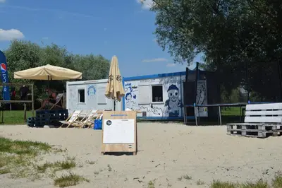 a beach with an umbrella and a sign in the sand at Dom Studencki Atol in Kraków