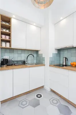 a kitchen with white cabinets and a tile floor at City of the Kings - Pastel Apartment Lubelska 10 in Kraków