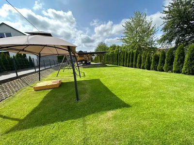 a lawn with a swing and an umbrella at Dom Wypoczynkowy przy Szlaku OJCÓW in Ojców