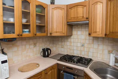 a kitchen with wooden cabinets and a stove top oven at Parkowa House in Kraków