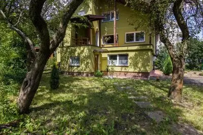 a yellow house with two trees in front of it at Parkowa House in Kraków