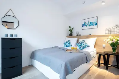 a bedroom with a bed with a blue blanket and a table at Kopernika8 Miro Apartment with Balcony and AC in Kraków