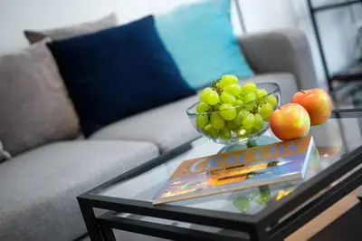a glass coffee table with a bowl of grapes and a book at Kopernika8 Miro Apartment with Balcony and AC in Kraków