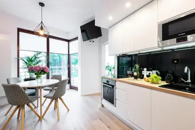 a kitchen with white cabinets and a table with chairs at Kopernika8 Miro Apartment with Balcony and AC in Kraków