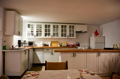a white kitchen with white cabinets and a table at Apartamenty Argo in Kraków