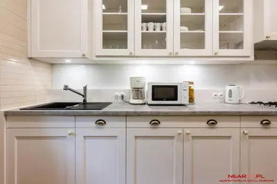a kitchen with white cabinets and a sink and a microwave at Apartment Nearto Old Town Daszyńskiego street in Kraków