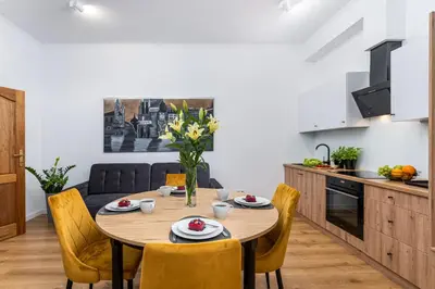 a kitchen and dining room with a wooden table and chairs at Beautiful Cracow Apartments by Cozyplace in Kraków