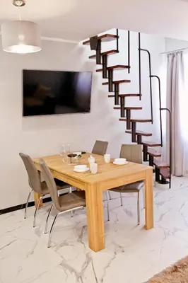 a dining room with a wooden table and a spiral staircase at Elegant City Center Apartment Pawlikowskiego 8 in Kraków