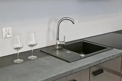 a kitchen counter with a sink and two wine glasses at Elegant City Center Apartment Pawlikowskiego 8 in Kraków