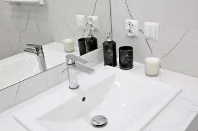 a white bathroom sink with two bottles on it at Elegant City Center Apartment Pawlikowskiego 8 in Kraków