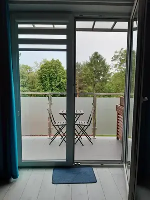 a patio door with a table and chairs on a balcony at Apartament FAMILY- klimatyzacja in Oświęcim