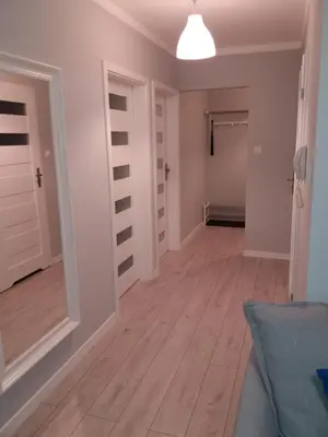 a hallway with white walls and a hardwood floor at Apartament FAMILY- klimatyzacja in Oświęcim