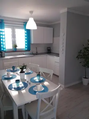 a white kitchen with a white table and chairs at Apartament FAMILY- klimatyzacja in Oświęcim