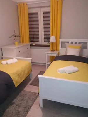 a bedroom with two beds with yellow curtains and a window at Apartament FAMILY- klimatyzacja in Oświęcim