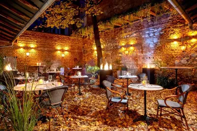 a restaurant with tables and chairs and a brick wall at Balthazar Design Hotel in Kraków