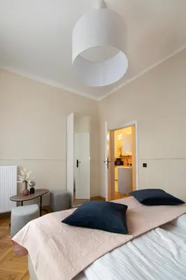 a white bedroom with a large bed and a table at Central Apartments Warszawska Street in Kraków
