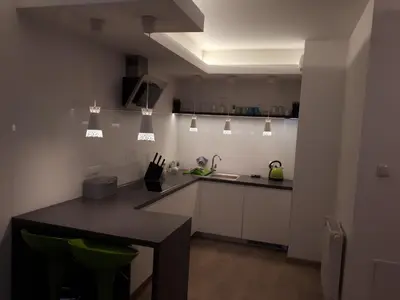 a kitchen with white cabinets and a black table at Wielicka Apartment in Kraków