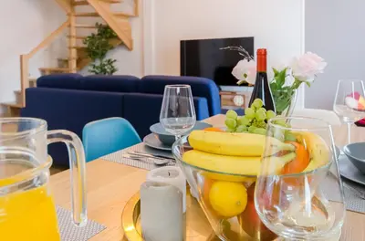 a table with a bowl of fruit and wine glasses at Kazimierz Penthouse with private terrace in Kraków