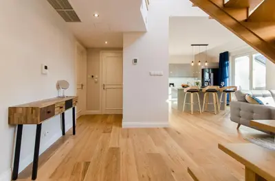 a kitchen and living room with white walls and wooden floors at Kazimierz Penthouse with private terrace in Kraków