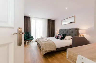 a bedroom with a bed and a green chair at Kazimierz Penthouse with private terrace in Kraków