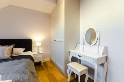 a bedroom with a bed and a dressing table with a mirror at Kazimierz Penthouse with private terrace in Kraków