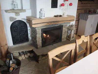 a fireplace in a living room with a stove at Chata Mioduszyna w Beskidach - drewniany dom z widokiem na Babią Górę in Maków Podhalański
