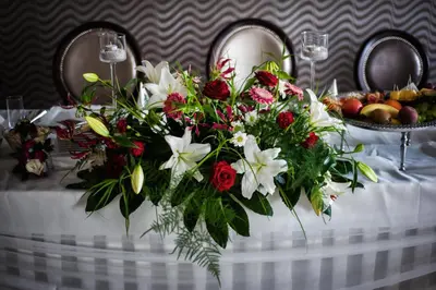 a white table with a bouquet of red and white flowers at Hotel Oriza in Gdów