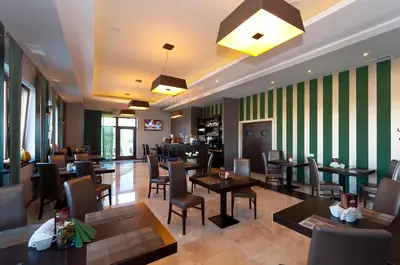a restaurant with tables and chairs and green stripes at Hotel Oriza in Gdów