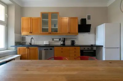a kitchen with wooden cabinets and a large wooden table at Prestige location apartments Pijarska street in Kraków