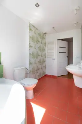 a bathroom with two toilets and two sinks and a red tile floor at Prestige location apartments Pijarska street in Kraków