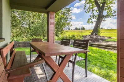 a wooden table and chairs on a patio with a field at Przystanek Zapotocze in Słopnice