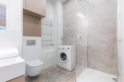 a white bathroom with a washing machine and a shower at Luksusowy apartament Świętego Jana na Rynku in Kraków