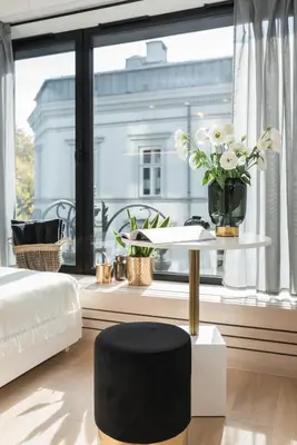 a bedroom with a table with a vase of flowers at White Room Piłsudskiego 1 in Kraków